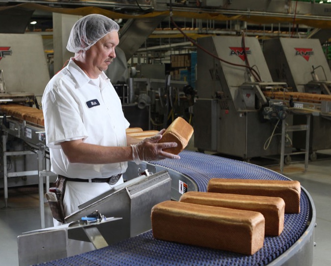 A factory worker inspects a loaf of bread at the Pan-O-Gold Baking Company factory in St. Cloud, MN.